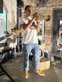 a man playing a trumpet in front of a brick wall